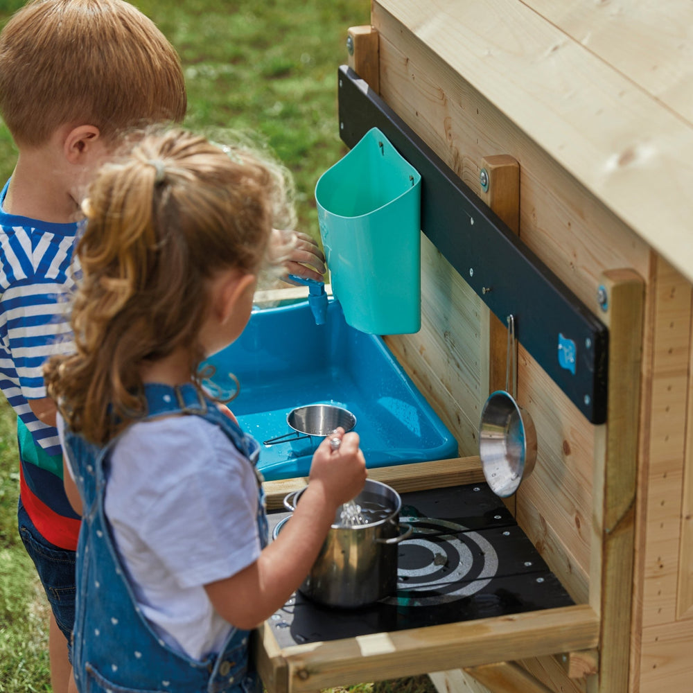 Children playing with wooden mud kitchen in the garden