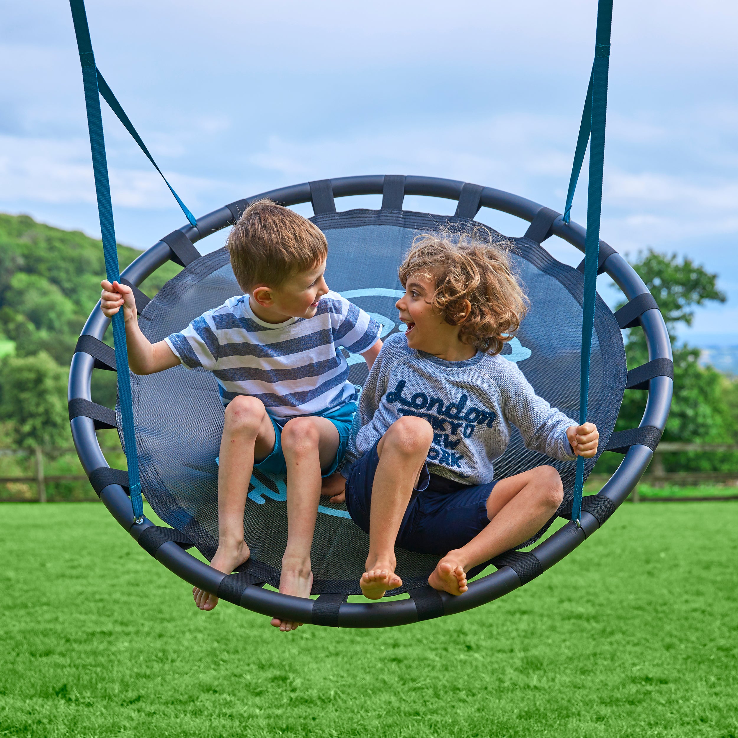 Two children swinging in a nest swing seat 