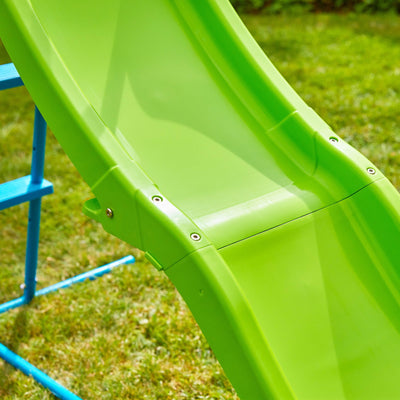 Close-up of the TP Toys TP Small to Tall Growable Slide, a bright green adjustable slide attached to a blue frame, set on a grassy lawn.