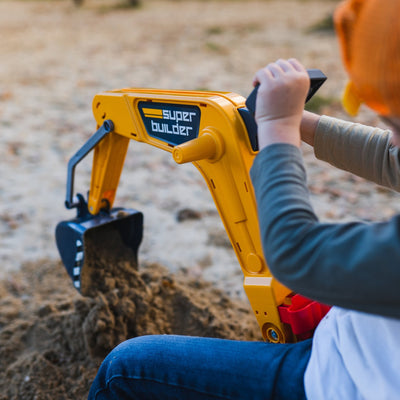 A child uses the TP Toys Falk Power Builder Digger with Opening Seat, labeled super builder, to scoop sand outdoors with its articulated mechanical shovel.