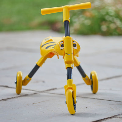 The TP Toys Scuttlebug Bumble Foldable Ride On Trike, featuring a yellow and black three-wheel design with cartoon eyes, is shown on a paved outdoor surface.