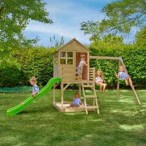 Five kids have fun in a leafy backyard with the TP Toys Buttercup Cottage Wooden Playhouse, featuring a deck, double swing arm, and 6ft wavy slide—FSC® certified for safe and sustainable play.