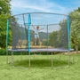 A child jumps with arms outstretched on the TP Toys TP Up 14ft Trampoline, safely enclosed by a net and set on a grassy lawn with trees in the background.