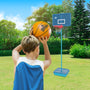 A boy in a blue jersey gets ready to shoot a basketball at a TP Toys Basketball All Surface Swingball hoop set up in the grassy backyard.