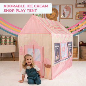 A young girl sits in front of the TP Toys Activo Ice Cream Shop Play Tent in a cozy living room. Perfect for imaginative play, this indoor-outdoor tent features a sign that reads "Adorable Ice Cream Shop Play Tent.