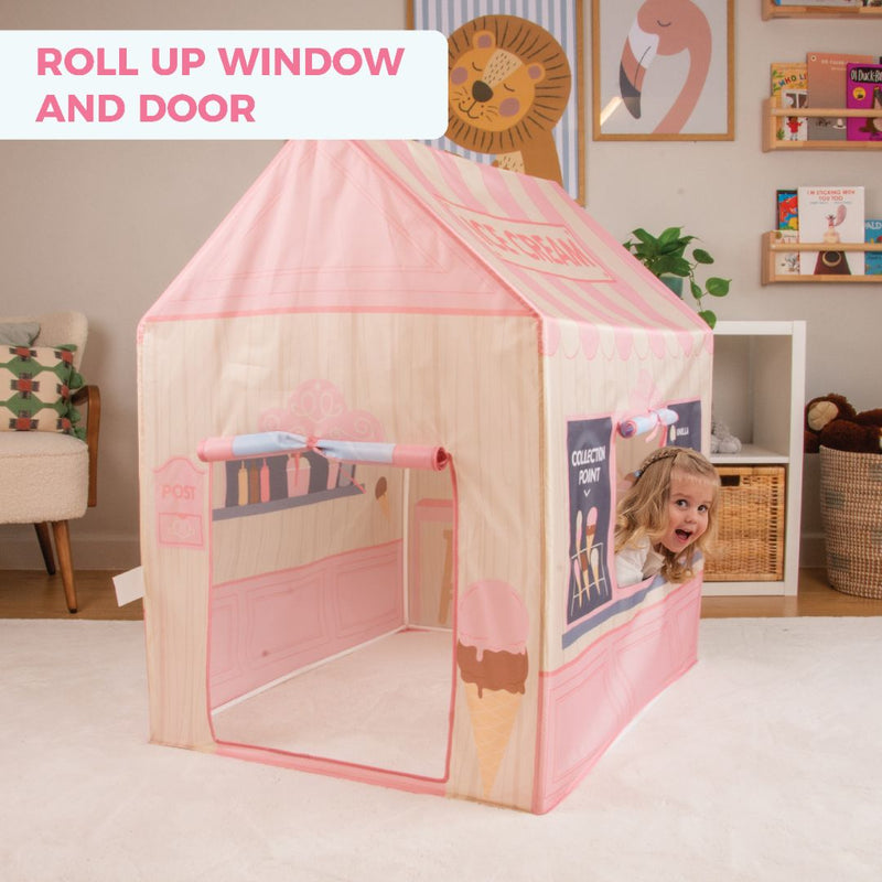 A child peeks from the TP Toys Activo Ice Cream Shop Play Tent, featuring pink and cream designs. Roll-up window and door make it perfect for imaginative indoor or outdoor playhouse fun.