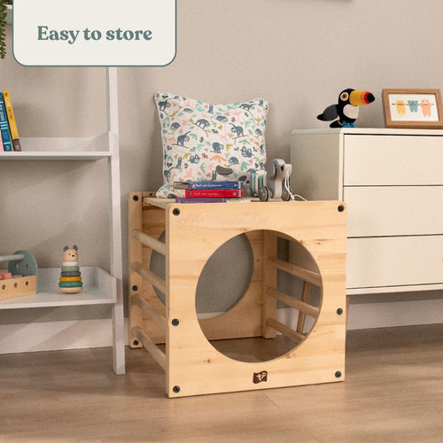 The TP Toys Active-Tots Pikler Style Wooden Climbing Cube – FSC® certified – is shown as a kids chair with a large circular opening, pillow, and books. The room features shelves, toys, and a drawer. Text: Easy to store.