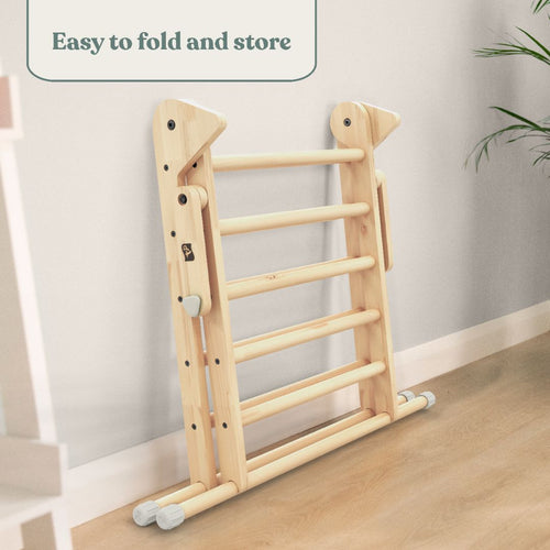 The TP Toys TP Active-Tots Pikler Style Wooden Climbing Triangle, FSC® certified, is folded and placed against a light wall, showing its compact, easy-to-store design—perfect as a Montessori or toddler climbing toy.