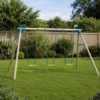 The TP Toys TP Sherwood Triple Wooden Swing Set – PEFC certified, featuring three green roped swing seats, is set up on a neatly mowed lawn in a backyard bordered by bushes, flowers, and a wooden fence.