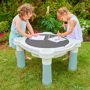 Two young children play with colored pencils on the Palplay Misty Sky Sand & Water Play Table by TP Toys in a garden, with flowers in the background.