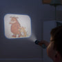 A child uses The Gruffalo Projecter by TP Toys to display cartoon monsters on a wall in a dimly lit room.