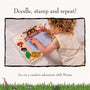 A young child draws with a pen on The Gruffalo Wooden Magnetic Drawing Board - FSC® certified by TP Toys, surrounded by colorful illustrations on a light surface.