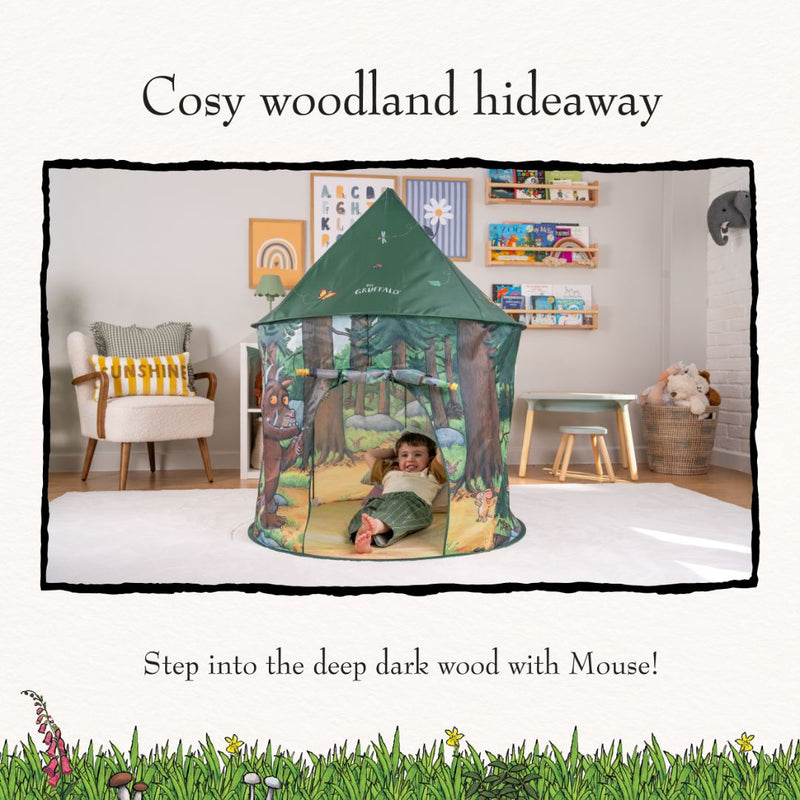 A child sits inside The Gruffalo Play Tent by TP Toys in a forest-themed setting, surrounded by toys, books, and furniture in the decorated living room—perfect for encouraging imaginative play.