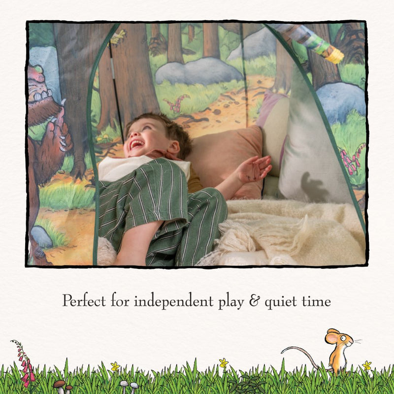 A young child lies inside the TP Toys The Gruffalo Play Tent, featuring enchanting forest illustrations, smiling and looking up; text below reads, Perfect for imaginative play & quiet time.