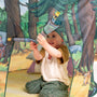 A young child sits inside the TP Toys The Gruffalo Play Tent, decorated with enchanting forest-themed artwork, holding a toy periscope and gazing upward, fully immersed in imaginative play.