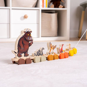 The Gruffalo Wooden Pull Along Character Set - FSC® certified by TP Toys features painted animal figures—including the Gruffalo, snake, owl, fox, and mouse—perfect for imaginative play. Resting on a light-colored carpet near shelves and baskets, this charming set not only delights as a pull-along toy but also works beautifully as a stacking character set to encourage creativity and fine motor skills.