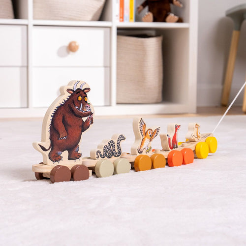 The Gruffalo Wooden Pull Along Character Set - FSC® certified by TP Toys features painted animal figures—including the Gruffalo, snake, owl, fox, and mouse—perfect for imaginative play. Resting on a light-colored carpet near shelves and baskets, this charming set not only delights as a pull-along toy but also works beautifully as a stacking character set to encourage creativity and fine motor skills.