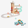 The TP Toys Owl & Fox Wooden Multi-storey Garage with Vehicle Transporter—crafted from FSC® certified wood—features cars, a spiral ramp, lift, and road for pretend play. Shown with a toy car carrier truck and cars beneath, this Montessori-inspired set encourages imaginative play and develops fine motor skills.