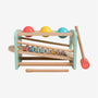 The Owl & Fox Wooden Xylophone Bench by TP Toys is an FSC® certified Montessori toy that includes a wooden xylophone, three colored balls, and a mallet; children use the mallet to strike the balls, sending them rolling down to play musical notes on the xylophone keys and helping to develop fine motor skills.