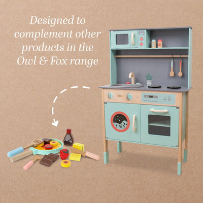 The Owl & Fox Wooden Pancake Set by TP Toys, made from FSC® certified wood, sits with a toy kitchen set featuring an oven, sink, and stove—perfect for pretend play and sparking imagination on a brown background.