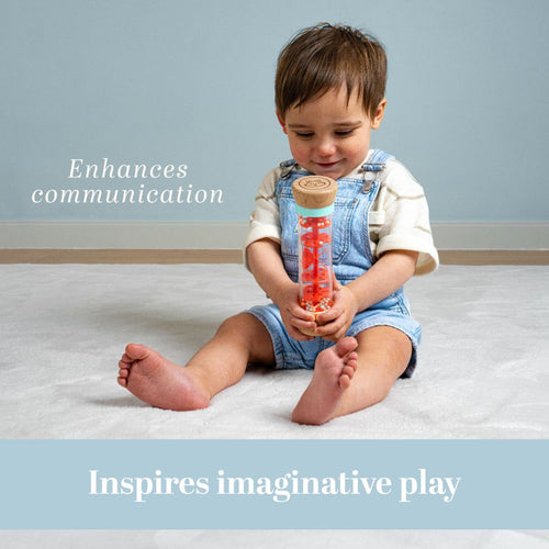 A young child sits on a light carpet, holding the Owl & Fox Wooden Rainmaker - FSC® certified by TP Toys. Text on the image reads: Enhances communication and inspires imaginative play, supporting sensory development.