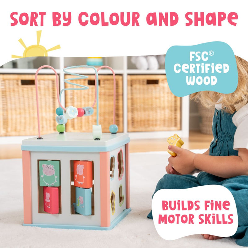 A child explores shapes and colors with the Grow with Peppa Pig Wooden Activity Cube by TP Toys, made from FSC certified wood and designed to develop fine motor skills through sensory play.