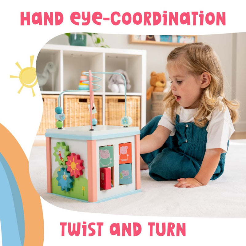 A young child enjoys the Grow with Peppa Pig Wooden Activity Cube by TP Toys, featuring gears and a bead maze in a bright room. Text reads: HAND EYE-COORDINATION, SENSORY EXPLORATION, TWIST AND TURN.