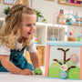 A young blonde girl explores sensory play on the floor with the TP Toys Grow with Peppa Pig Wooden Activity Cube, using its colorful bead and shape puzzles to develop her fine motor skills.