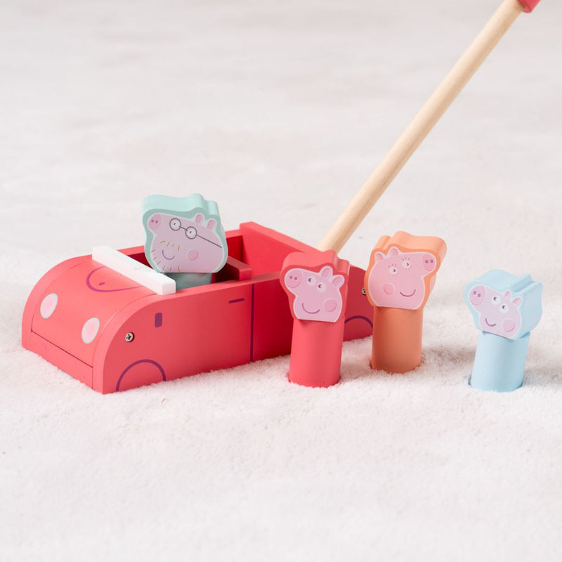 The TP Toys Grow with Peppa Pig Wooden Push Along Family Car features four colorful wooden character pegs and a wooden mallet, shown here on a light carpeted surface.