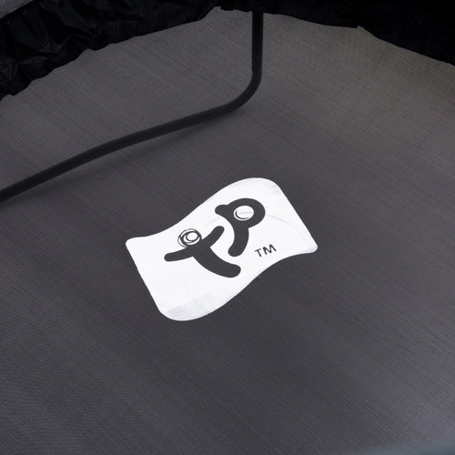 A close-up of the TP Toys Genius® 8ft Round Trampoline mat shows a white square logo with stylized black lettering and trademark symbol, emphasizing the trampoline's safety features.