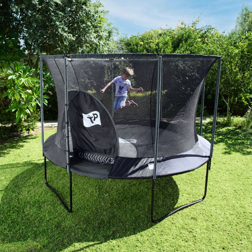A child jumps on a TP Genius® 10ft Round Trampoline by TP Toys, featuring safe zip-free entry, in a grassy backyard surrounded by green trees and bushes.