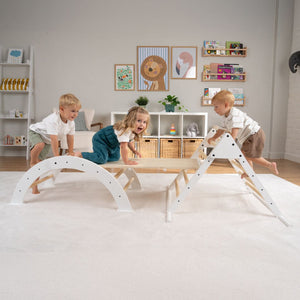 Three young children climb and play on the TP Toys TP Active-Tots Pikler Style Three in One Playset (FSC® certified) in a brightly lit, neatly decorated room with shelves and wall art.