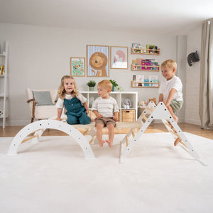 Three children play on the TP Toys TP Active-Tots Pikler Style Three in One Playset—FSC® certified—in a bright living room decorated with animal-themed art and toys.