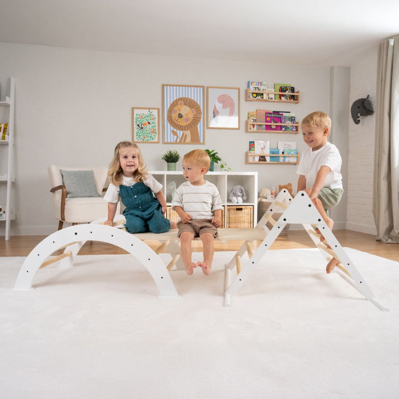 Three children play on the TP Toys TP Active-Tots Pikler Style Three in One Playset—FSC® certified—in a bright living room decorated with animal-themed art and toys.