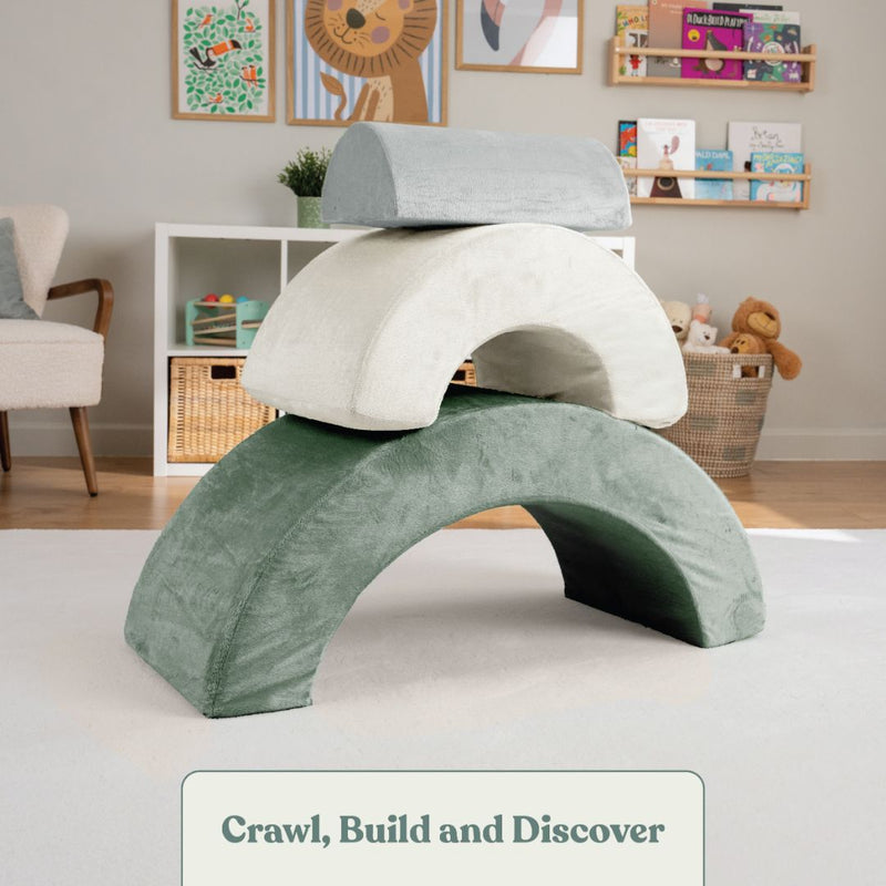 Three TP Toys Active-Tots Pikler Style Rainbow Arch Playsets are stacked in a playroom with books, toys, baskets, and animal art in the background. The text “Crawl, Build and Discover” encourages gross motor skill development.