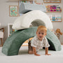 A young child crawls under the TP Toys TP Active-Tots Pikler Style Rainbow Arch Playset in a living room, building gross motor skills with this Montessori-inspired toddler play equipment.