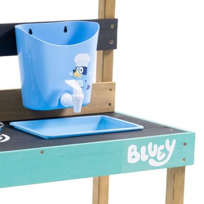 The TP Toys Bluey Wooden Mud Kitchen - FSC® certified, features a blue plastic sink with a cartoon dog chef, faucet, blue tray, and "BLUEY" on the front—perfect for fun garden playsets and inspired by the Bluey Mud Kitchen series.