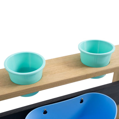Two light blue plastic cups sit in circular cutouts on a wooden board with a blue container below, making the TP Toys Bluey Wooden Mud Kitchen - FSC® certified a perfect addition to any garden playset.