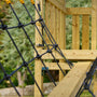 Close-up of the TP Toys Skywood Wooden SkyWalk Bridge, crafted from FSC® certified wood with a black rope climbing net and railings; blurred trees appear in the background.