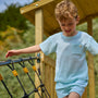 A young boy in a light blue t-shirt and shorts walks across the TP Toys Skywood Wooden SkyWalk Bridge—FSC® certified—in an outdoor playground.