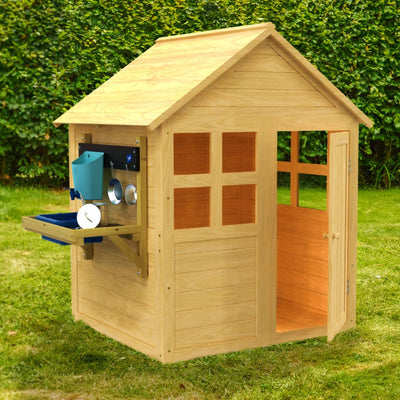 The TP Toys Buttercup Cottage Wooden Playhouse with Floor and Mud Kitchen - FSC® certified, features an open door and window, mud kitchen on one side, and is pictured on grass with bushes in the background.