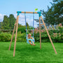 A baby sits in the TP Toys TP Sherwood Single Wooden Swing Set with Bluey Quadpod—PEFC certified—on a grassy lawn, surrounded by trees and bushes.