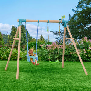 A baby sits on the TP Toys Bluey Quadpod growable seat, part of the TP Sherwood Wooden Double Swing with Roped Rapide Seat, PEFC certified, in a garden with green grass and flowers on a clear day.