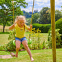 A young girl in a yellow shirt and denim shorts smiles as she swings on the Bluey Quadpod seat, part of the TP Sherwood Wooden Double Swing with Roped Rapide Seat by TP Toys, made from PEFC certified roundwood in a sunny garden.