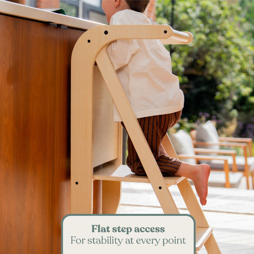 A toddler stands on a wooden TP Active-Tots Pikler Style Wooden Helper Tower with text overlay reading Flat step access, For stability at every point.