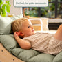 A young child reclines on the TP Toys Active-Tots Sway Wooden Rocker with Cushion (FSC® certified), smiling and looking relaxed indoors. Text above reads, Perfect for quiet moments.