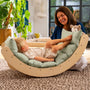 A child relaxes on the TP Toys TP Active-Tots Sway Wooden Rocker with Cushion—FSC® certified—while an adult sits nearby, smiling and holding a plush toy in a bright, modern living room.