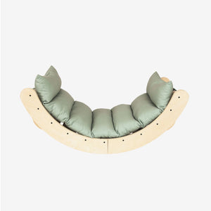 TP Toys TP Active-Tots Sway Wooden Rocker with Cushion – FSC® certified, featuring a curved wooden design with a light green cushion and four pillows, photographed against a plain white background.