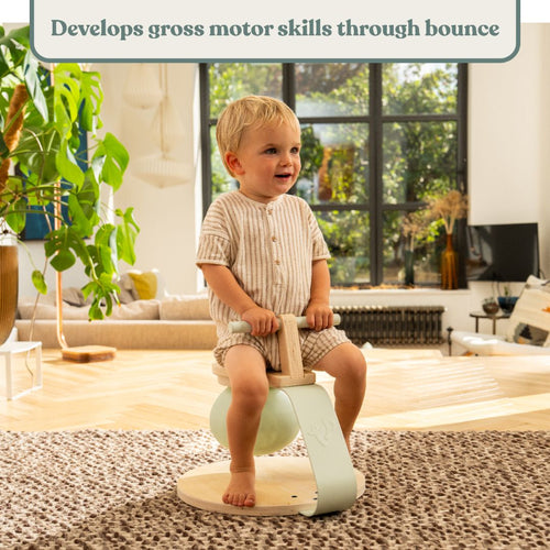 A young child sits on the TP Toys TP Active-Tots Pikler Style Toddler Bouncer—crafted from FSC® certified wood—in a bright living room. Text above reads, Encourages gross motor skill development through active bouncing.