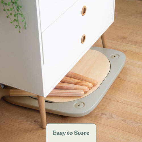 The TP Toys Active-Tots Pikler Style 4 in 1 Wooden Play Table is neatly stored under a white cabinet with plant decor, showing how this FSC® certified kids’ table saves space on a wooden floor.